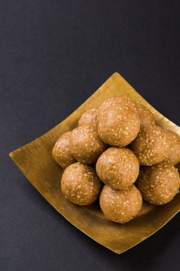 Hint susam tatlı veya tilgul laddu, jaggery ve susam oluşan, Makar Sankranti festivali için hint tatlı, jaggery & çiğ susam ile terracotta kase