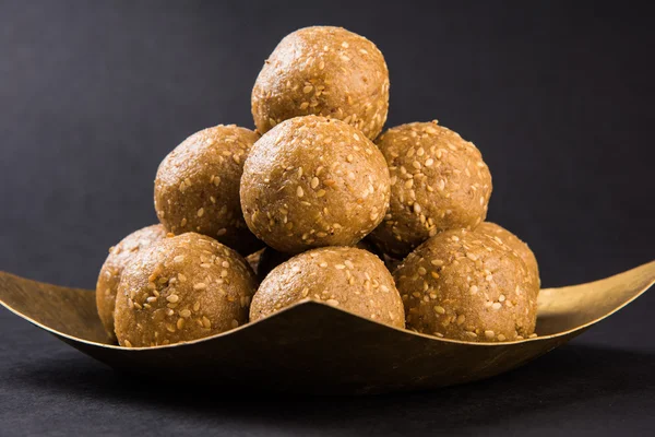 The indian sesame sweet or tilgul laddu, made up of jaggery and sesame seeds, indian sweet for Makar Sankranti festival, in terracotta bowl with jaggery & raw sesame