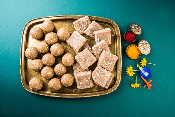 Laddu sésame ou tulgul ou til gul laddu ou ladu dans une assiette en laiton avec huldi et kumkum, fête traditionnelle indienne en janvier, cuisine sucrée indienne, rituels indiens, gâteau au tilgul ou vadi — Photo