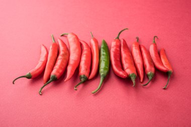 dipicting benzersiz kavramı, farklı konsepti, özel konsept, özgünlük kavramı, taze kırmızı ve yeşil biber, biber izole yeşil zemin üzerine kullanarak akış kavramı karşı