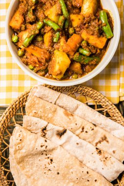 hint tarifi, geleneksel masala ve köri ile patates ve fasulye içeren karışık sebze, kırmızı sıcak ve baharatlı geleneksel chapati / fulka / hint roti / seramik plaka izole hint ekmeği ile servis