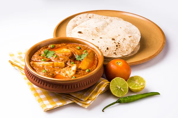 Kari kentang atau aalu masala atau aaloo masala dengan kacang polong hijau, disajikan dengan roti India / roti / chapati / naan / fulka / phulka — Stok Foto