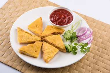 Ekmek Pakora veya ekmek pakoda domates ketçap yeşil soğuk ve soğan dilimleri ile birlikte servis, hint çerez, yeşil paspas üzerinde beyaz tabakta servis, izole ön görünüm, beyaz arka plan