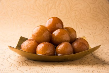 Gulab Jamun served in a square brass plate with pouring sweet syrup - An Indian sweet dish, round shaped, black or brown texture served as a dessert, high calories, diwali food clipart