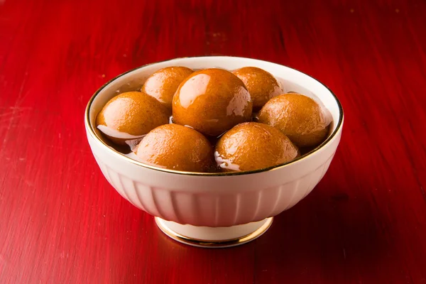 Gulab Jamun disajikan dalam piring kuningan persegi dengan menuangkan sirup manis - Sebuah hidangan manis India, berbentuk bulat, tekstur hitam atau coklat yang disajikan sebagai makanan penutup, kalori tinggi, makanan diwali — Stok Foto