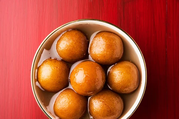 Gulab Jamun disajikan dalam piring kuningan persegi dengan menuangkan sirup manis - Sebuah hidangan manis India, berbentuk bulat, tekstur hitam atau coklat yang disajikan sebagai makanan penutup, kalori tinggi, makanan diwali — Stok Foto