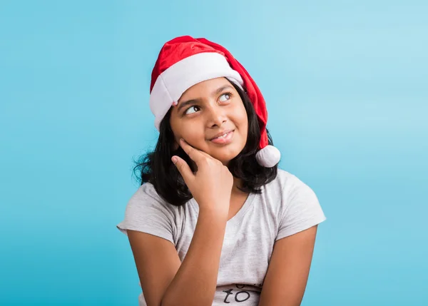 Small cute indian girl with christmas hat, thinking, indian girl and christmas, christmas and india, indian kids and christmas, indian kids celebrating christmas, asian girl and christmas, thinking — Stock Photo, Image