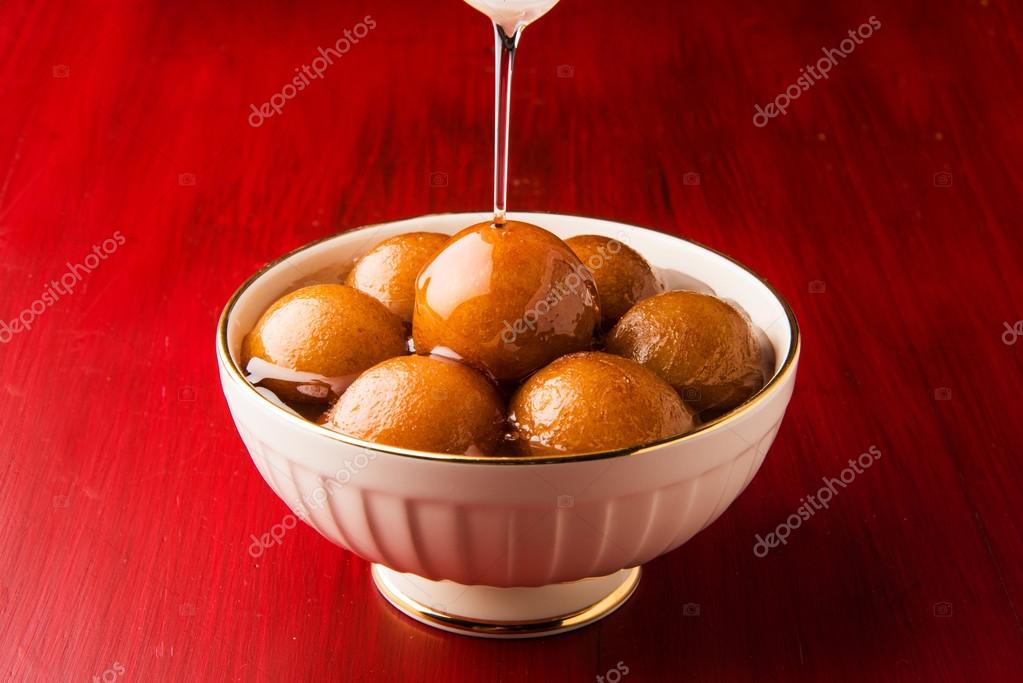 Gulab Jamun served in a square brass plate with pouring sweet syrup - An  Indian sweet dish, round shaped, black or brown texture served as a  dessert, high calories, diwali food Stock