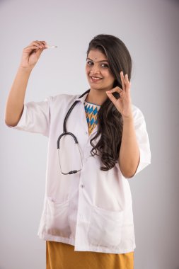 Hintli kadın doktor termometre, Asya kadın doktor ve termometre, termometre, kullanarak Hintli genç tıp doktoru kontrol ateş ile izole gri arka plan üzerinde