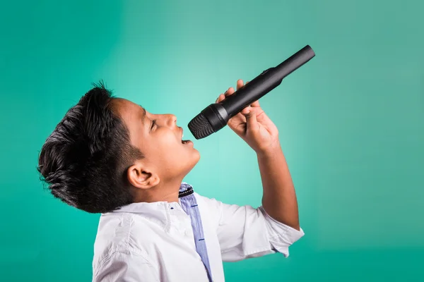 Joven indio chico en camisa blanca gritando en micrófono, niño pequeño cantando, pequeño indio chico con micrófono canta una canción, cantando asiático joven chico, lindo joven asiático chico cantando en un micrófono — Foto de Stock