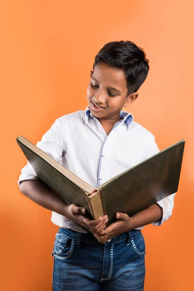 Enfant indien appréciant le livre de lecture, enfant asiatique lisant le livre, enfant africain lisant le livre, enfant indien étudiant, enfant indien tenant le livre, portrait, enfant indien debout avec le livre, livre de géographie, dos orange — Photo