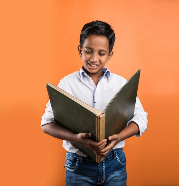 Indian kid enjoying reading book, asian kid reading book, african kid reading book, indian kid studying, indian kid holding book, portrait, indian kid standing with book, geography book, orange back