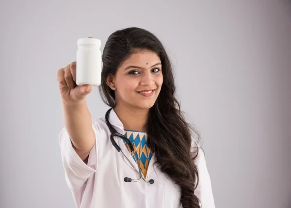 Indisk kvinnlig läkare som håller upp en vit flaska tabletter, Asiatisk kvinnlig läkare som visar vita piller flaska, lämplig för reklam, isolerad på grå bakgrund — Stockfoto
