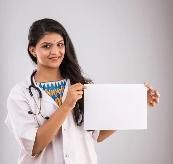 Indiska läkare kvinna leende med stetoskop håll tomt tomt visitkort, begreppet reklam produkt, tom kopia utrymme. Isolerad på grå bakgrund, indiska Lady Doctor hålla blank kort, Asiatiska — Stockfoto