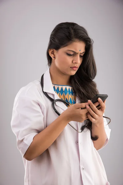 Indiska kvinnliga läkare med smartphone, asiatiska läkare med smartphone, isolerad på grå bakgrund — Stockfoto