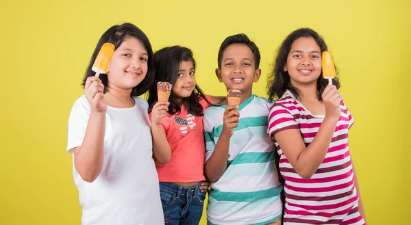 Vier süße kleine indische Kinder, die Eis essen, asiatische Mädchen und Jungen und Eis, isoliert auf grünem Hintergrund — Stockfoto
