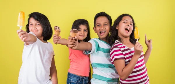 Vier süße kleine indische Kinder, die Eis essen, asiatische Mädchen und Jungen und Eis, isoliert auf grünem Hintergrund — Stockfoto