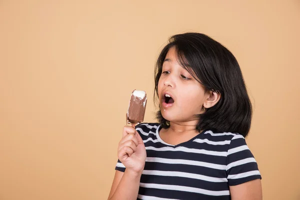 Indiase meisje eten ijs of ijs snoep, Aziatisch meisje en ijs of ijs snoep, geïsoleerd op bruine achtergrond, tien jaar oud Indiase meisje genieten van ijs — Stockfoto