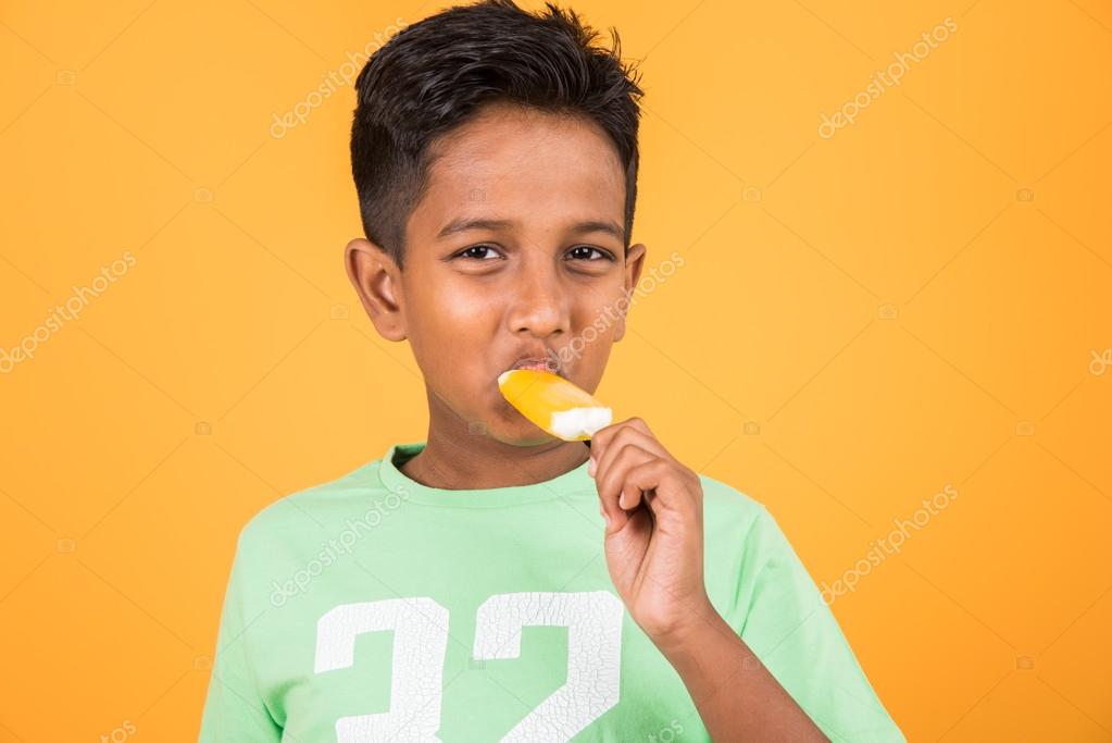 Little Indian Boy Eating Ice Lolly Or Ice Candy Indian Boy Eating Mango Ice Cream Asian Boy And Orange Ice Candy Isolated On Yellow Background 10 Year Boy And Ice Cream Stock
