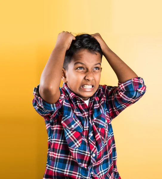 indian kid and headache or cephalalgia, asian kid and headache or cephalalgia, indian kid holding head, indian kid pulling hair in pain and stress, red background, 10 year indian boy