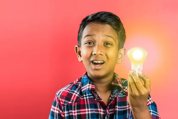 10 ans garçon indien tenant ampoule lumineuse dans la main, concept de créativité, concept de science, idées en cliquant sur les expressions, garçon indien, garçon asiatique, fond rouge, profil avant, gros plan — Photo