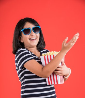 mutlu kız patlamış mısır yeme ve gözlük takan, hint kız patlamış mısır, asyalı kız ve patlamış mısır, kırmızı arka plan üzerinde patlamış mısır yeme hint kız