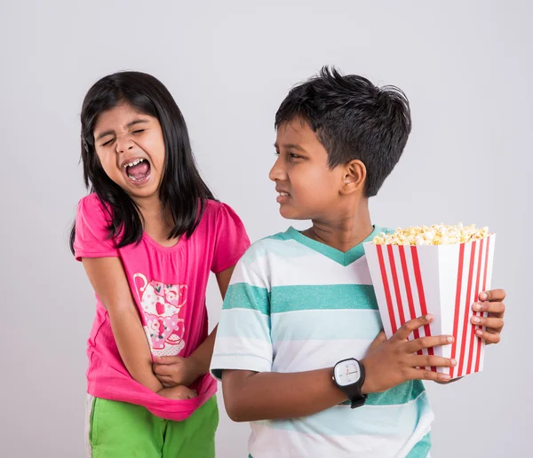 Asiatique petit garçon et fille regarder film avec pop corn, petite fille indienne assis avec frère regarder film manger pop corn, enfants indiens manger pop corn, enfants regarder film avec pop corn — Photo
