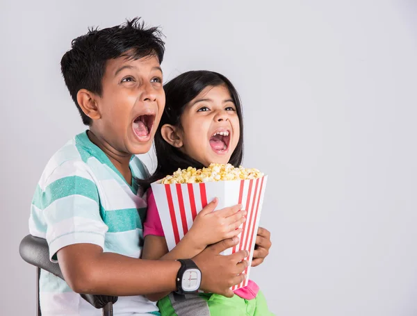 Asian little boy and girl watching movie with pop corn, little indian girl sitting with brother watching movie eating popcorn, indian kids eating pop corn, kids watching movie with pop corn — Stock Photo, Image