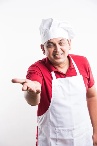 Портрет красивого індійського кухаря-чоловіка, який представляє щось, що досягає камери, азіатський кухар-чоловік представляє щось, ізольоване на білому тлі — стокове фото