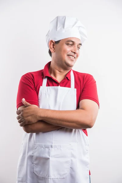 Retrato de chef masculino indiano bonito e alegre em uniforme com as mãos dobradas, isolado sobre fundo branco, foco seletivo no olho, espaço de cópia — Fotografia de Stock