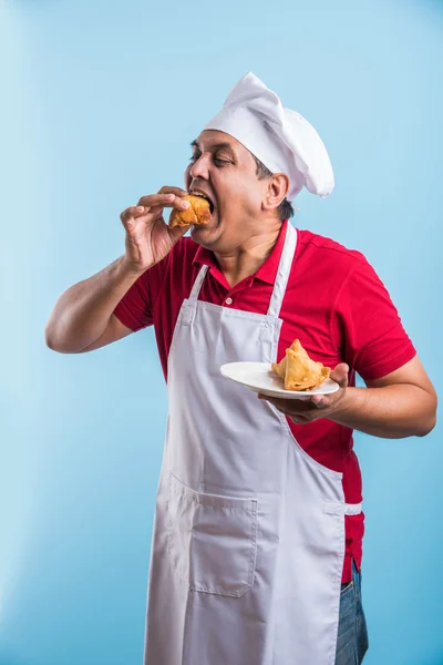 indian male chef tasting indian snack samosa, asian male chef cook and food in plate