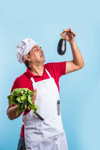 Indiana masculino chef segurando fresco couve-flor e espinafre folhas, de pé isolado sobre azul fundo, asiático masculino chef segurando fresco legumes — Fotografia de Stock