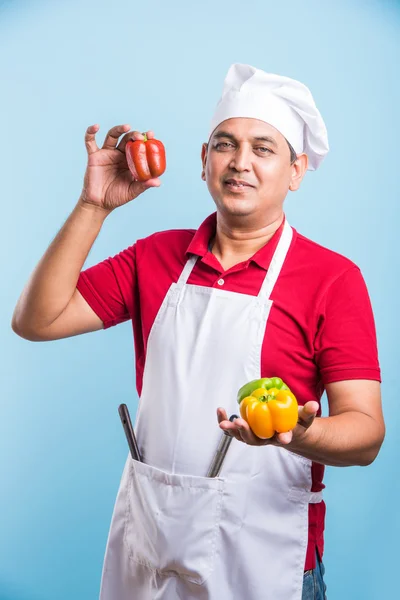 Indiana Masculino chef mostrando capsicum, asiático masculino cozinheiro chef e colorido capsicum, isolado sobre fundo azul — Fotografia de Stock