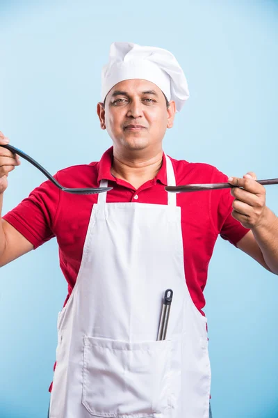 Joven Chef Holding cuchara skimmer y cuchara de madera aislado sobre fondo azul — Foto de Stock