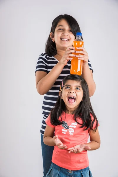 two indian girls with cold drink bottle, two asian girls posing with cold drink in pet bottle, 2 girl kid and cold drink, indian cute girls feeling coldness of mango juice or orange juice bottle