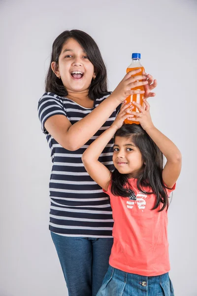 Two indian girls with cold drink bottle, two asian girls posing with cold drink in pet bottle, 2 girl kid and cold drink, indian cute girls feeling coldness of mango juice or orange juice bottle — Stock Photo, Image