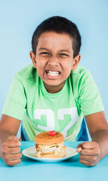 Schattige Indiase jongen eten hamburger, kleine Aziatische jongen en Hamburger, over blauwe achtergrond — Stockfoto