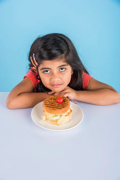 Schattig Indisch meisje eten hamburger, kleine Aziatische meisje en Hamburger, geïsoleerd over gele achtergrond — Stockfoto