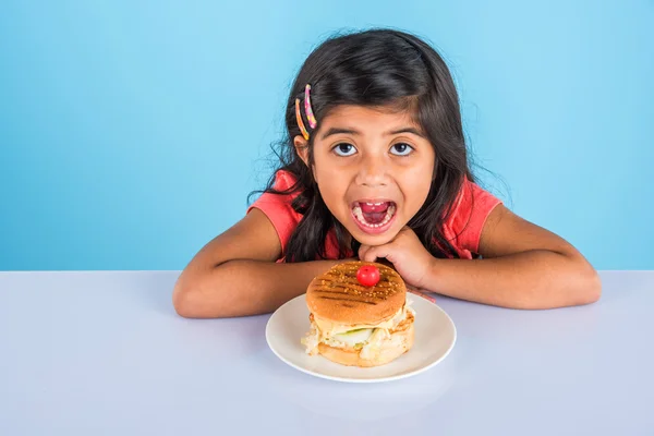 Schattig Indisch meisje eten hamburger, kleine Aziatische meisje en Hamburger, geïsoleerd over gele achtergrond — Stockfoto