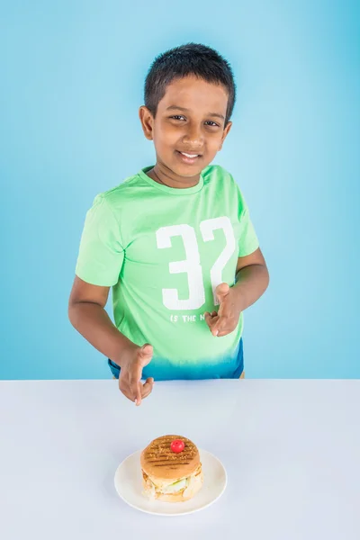 Schattige Indiase jongen en Hamburger in kleine witte plaat, kleine Aziatische jongen en Hamburger, over kleurrijke achtergrond — Stockfoto