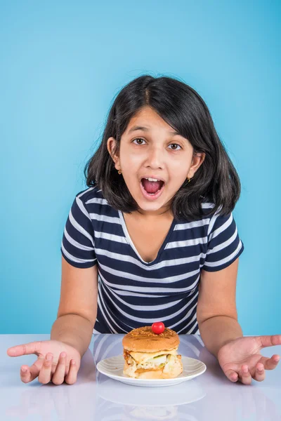 Schattig Indiase meisje eten hamburger, klein Aziatisch meisje en Hamburger, geïsoleerd op kleurrijke achtergrond — Stockfoto