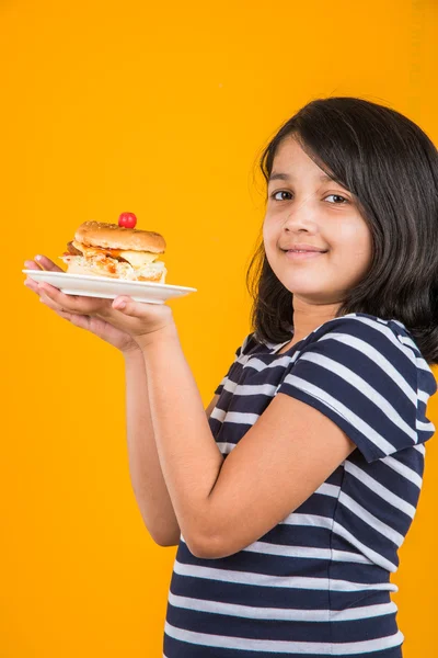 Schattig Indiase meisje eten hamburger, klein Aziatisch meisje en Hamburger, geïsoleerd op kleurrijke achtergrond — Stockfoto