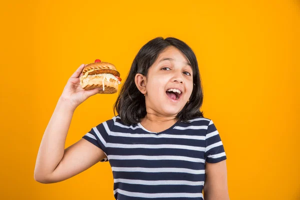 Schattig Indiase meisje eten hamburger, klein Aziatisch meisje en Hamburger, geïsoleerd op kleurrijke achtergrond — Stockfoto