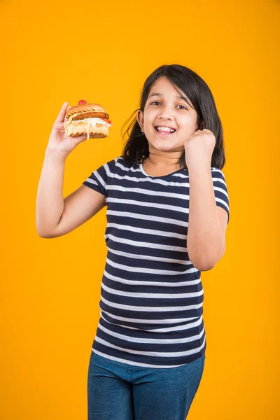 Schattig Indiase meisje eten hamburger, klein Aziatisch meisje en Hamburger, geïsoleerd op kleurrijke achtergrond — Stockfoto