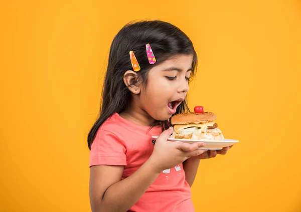 Schattig Indisch meisje eten hamburger, kleine Aziatische meisje en Hamburger, geïsoleerd over gele achtergrond — Stockfoto