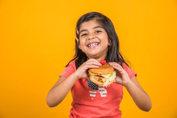 Schattig Indisch meisje eten hamburger, kleine Aziatische meisje en Hamburger, geïsoleerd over gele achtergrond — Stockfoto