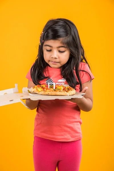 Portret van de schattige Indiase meisje houden een open doos van pizza, opgewonden Aziatische meisje opening pizzadoos met glimlach op gezicht, staande over gele achtergrond — Stockfoto