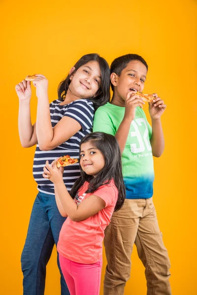 Tres o tres niños indios pizza sobre fondo amarillo — Foto de Stock