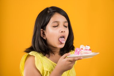 kek ya da pasta, kek, kız sarı arka plan üzerinde çilek pasta yemek yeme sevimli küçük kız yemek Hint çocuk portresi