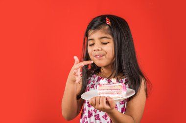 kek ya da pasta, kek, kırmızı arka plan üzerinde çilek pasta yemeye kız yiyen sevimli küçük kız yemek Hint çocuk portresi